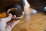 The substantial C-shape and warm patina of an antique African copper bracelet.