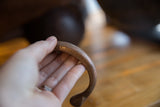 Antique copper cuff held in hand to detail its hand-wrought texture.