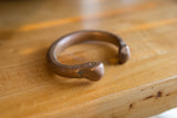 Aged patina and stamped markings on the end of a copper snake cuff bracelet.