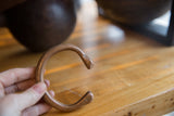 Antique African copper cuff held in hand, showing its C-shape and aged patina.