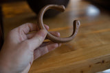Handcrafted details and unique C-shape of an antique copper snake cuff bracelet.