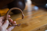 Antique copper snake cuff bracelet held to show its open shape and rich patina.