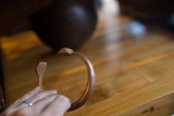 Antique African copper snake bracelet held to show its profile and scale.