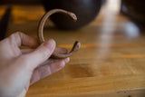 Antique copper snake cuff bracelet held in hand, showing its form and snake-head ends.