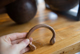 A hand holds the antique copper snake cuff, highlighting its etched band and form.