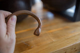 The hand-carved snake head and etched band of an antique African copper cuff.