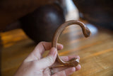 The curved profile and hand-etched details of an antique copper snake cuff.