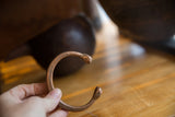 Antique African copper snake cuff bracelet held to show its handmade form and patina.