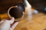 In-hand view of an antique copper snake cuff, showing its handcrafted form and patina.