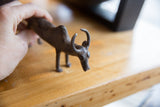 A hand holds the vintage bronze zebu, showing its scale and texture.