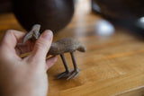 Vintage bronze kori bustard bird held in hand, showing its textured surface and scale.