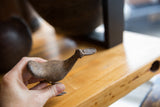 Hand holding vintage African bronze flat billed bird, highlighting its texture.