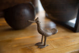 Profile view of the handmade bronze bird showing its aged, textured surface.