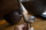 Vintage African bronze bird held to show its handmade form and aged patina.