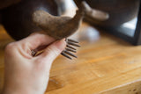 Hand holding the vintage African bronze bird, highlighting its textured, fork-like tail.