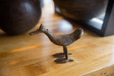 Vintage African bronze bird sculpture showing its aged, textured patina from a side profile.