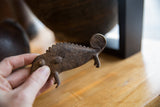 Vintage African bronze chameleon held in hand, showing textured body, ridged back, and coiled tail.