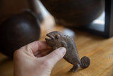 Hand holding a vintage African bronze chameleon, showing its etched body and golden eye.