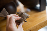 A hand holding a vintage African bronze fish, showing its rustic handmade texture.
