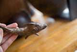 Detailed view of a vintage bronze fish's head, showing textured scales and aged patina.