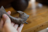 Vintage African bronze fish, showing textured head, eye, and aged patina held in hand.