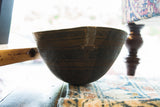 Side view of vintage African wooden bowl, showing etched texture and metal repair.