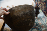 Vintage African wooden bowl detail showing hand, horizontal carved lines, and rich patina.