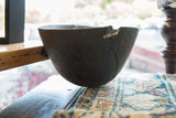 Detail of the vintage African wooden bowl's chipped edge with metal repair.