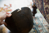 Aged dark African wooden bowl with prominent crack and metal repair.