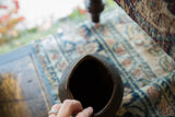 Looking down into the dark, hand-carved opening of a vintage wooden pitcher.