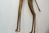 Detail of the vintage bronze giraffe's stylized legs, hooves, and slender tail.