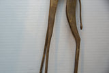 Detail of the vintage bronze giraffe's slender legs and tail, showing an aged patina.