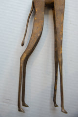 Detail of the vintage bronze giraffe's stylized back legs and tail, with a naturally aged patina.