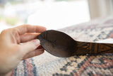 Hand-carved linear and geometric designs inside the dark wood bowl of the spoon.