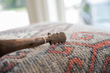 Detail of the aged, dark wood and jagged, hand-carved design on the vintage spoon's head.