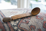Full length view of a vintage African wooden spoon highlighting its rich, dark wood patina.