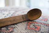 Carved line details on the aged, dark wood handle of a vintage African spoon.