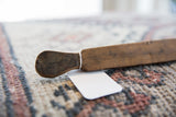 The aged texture and dark patina on the hand-carved head of a vintage wooden spoon.