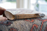 Aged wood grain and incised carvings on the handle of the vintage African spoon.