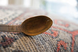 Carved decorative lines and an aged crack inside the bowl of a vintage African wooden spoon.