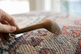 Side profile of the vintage African spoon showing its aged wooden texture and curve.