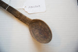 Vintage Tuareg wooden spoon with its dark, aged texture and handwritten item tag.