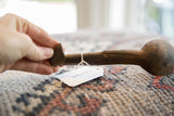 A hand holding the dark, textured handle of a vintage African wooden spoon.