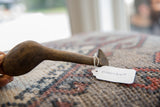 Profile of a vintage African wooden spoon showing its dark wood grain and attached item tag.