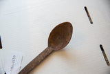 Angled view of the vintage wooden spoon's textured bowl and carved handle details.