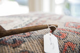 A paper item tag tied with string to the handle of a vintage wooden spoon.