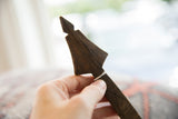 The pointed, hand-carved finial of a vintage African wooden spoon.