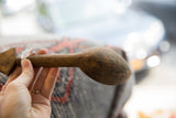 A vintage handmade African wooden spoon held, showing its aged patina and shape.