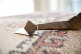 Hand-carved geometric lines on the aged, dark wood handle of a vintage spoon.