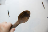 Detailed view of the aged, dark wood and carved texture within the spoon's bowl.